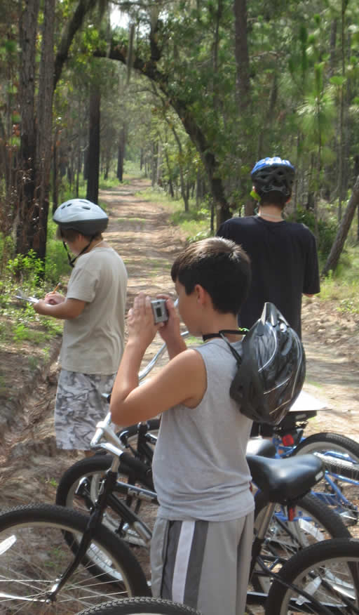 Three campers taking photos on a bike tour.